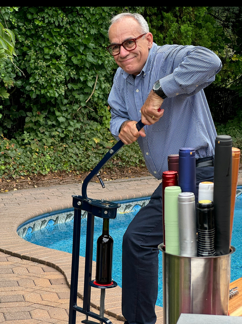 Man using wine corker, about to close bottle with others nearby