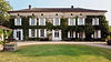 Beautiful ivy-clad chateau with white shutters, green lawn, and stone well.