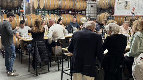 Group of people enjoying wine tasting at winery with barrels and U Design