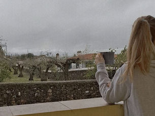 Mulher numa varanda a beber chá com vista para um olival