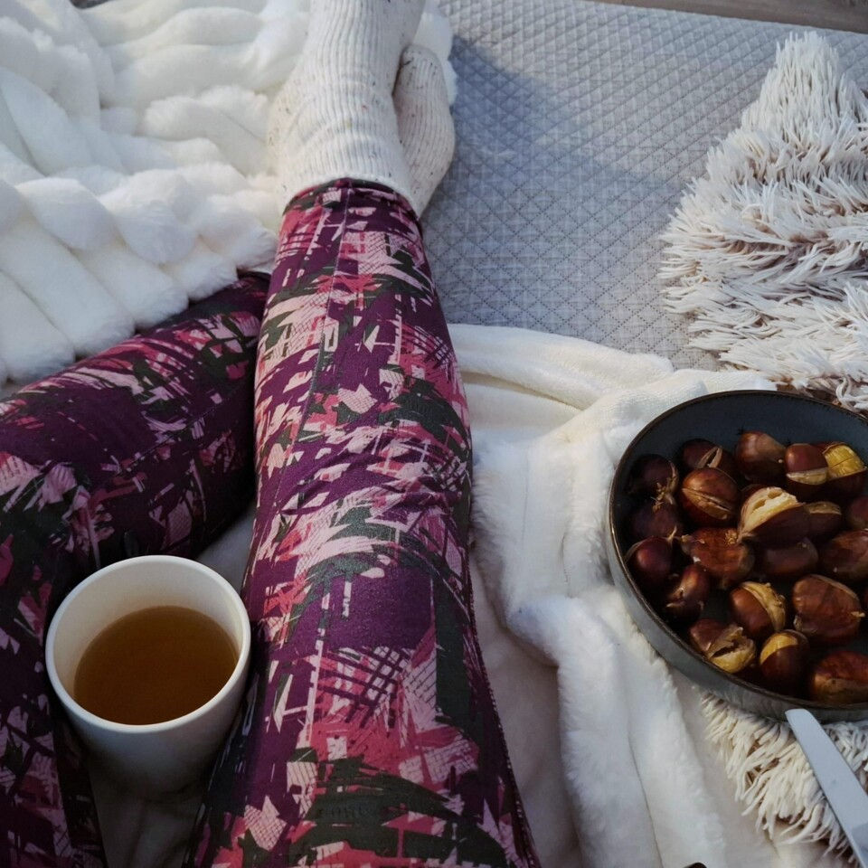 pernas, castanhas assadas e chá num sofá com uma manta