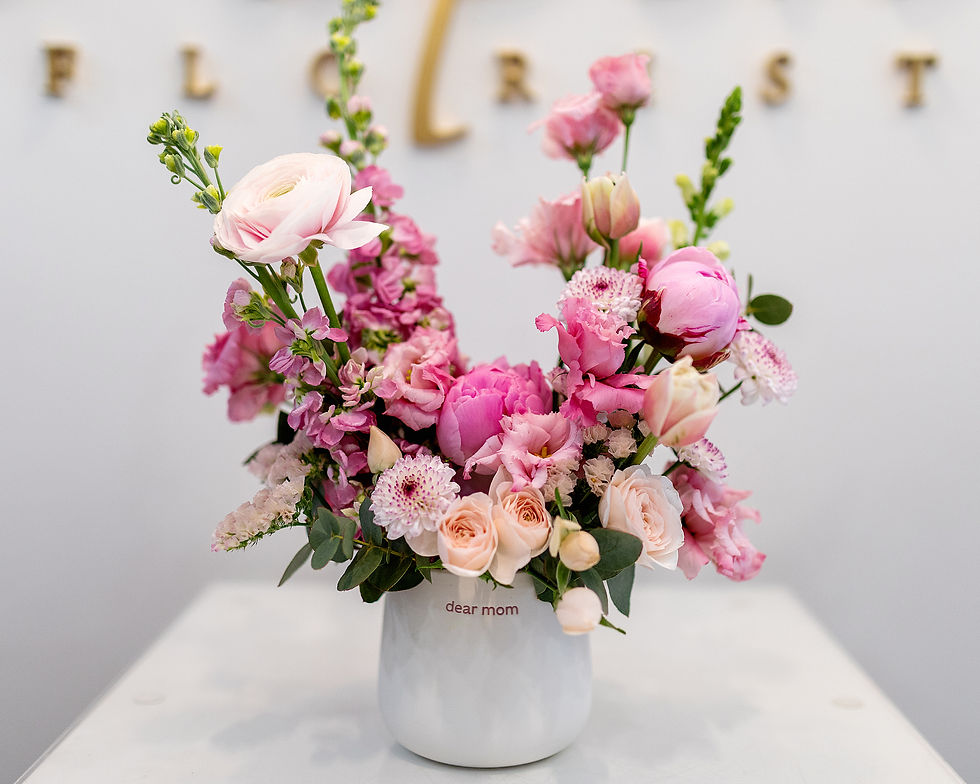 Floral arrangement in a ceramic vase with “dear mom” on the front