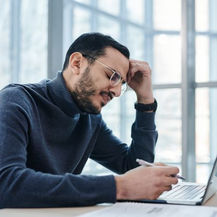  Man feeling overwhelmed while working at a desk with a laptop