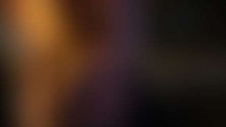 Close-up of a person smoking a lit cigarette, emitting faint smoke. The background is dark, creating a moody atmosphere.