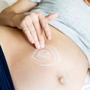 Pregnant woman applying moisturising belly oil as part of a gentle pregnancy skincare routine