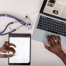 Healthcare professional comparing medical research on a laptop and tablet