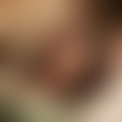 Woman in green top lying calmly on a pillow while receiving Reiki therapy, as practitioner’s hands gently hover above her body in a peaceful beige setting, highlighting calming therapist skills.