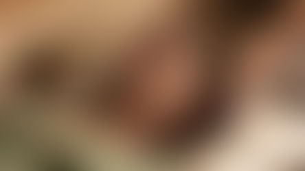 Woman in green top lying calmly on a pillow while receiving Reiki therapy, as practitioner’s hands gently hover above her body in a peaceful beige setting, highlighting calming therapist skills.