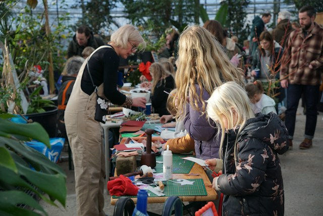 Adults and children completing crafts together around tables in a community setting.