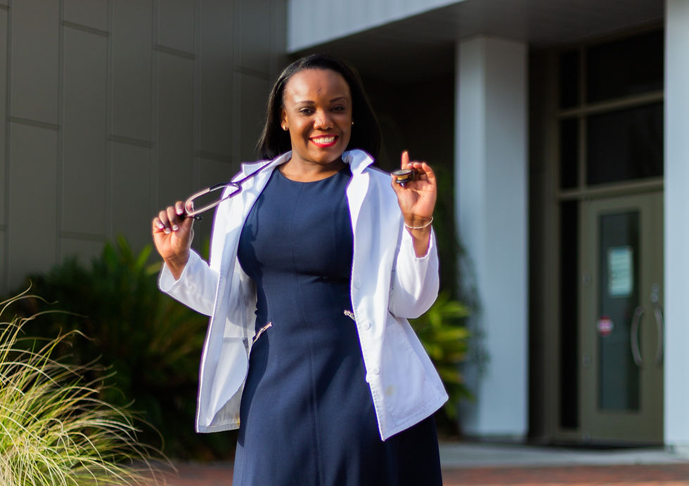 Smiling nurse in a white coat and navy dress holding a stethoscope, standing outside a building with greenery, representing nurses in wellness business opportunities.