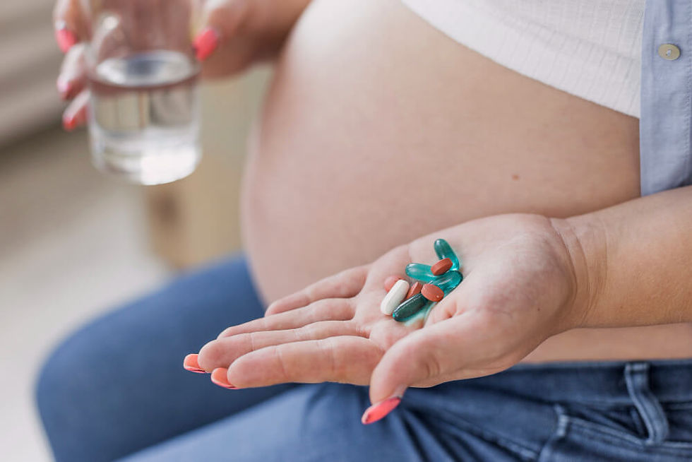 Pregnant woman taking prenatal or postnatal vitamins with a glass of water.