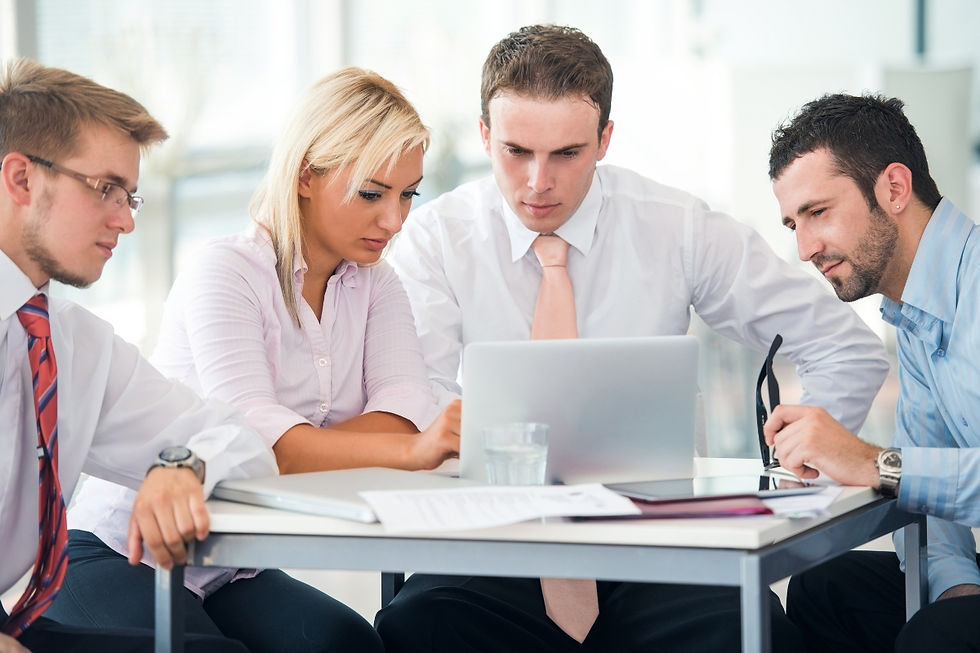 A group of Travel agents sitting around a table looking at a laptop