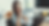 Woman in glasses smiling at laptop, hands clasped, in bright living room. A modern interior with blurred background. Mood is cheerful.