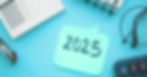 Sticky note with "2025" on a blue background, surrounded by a notepad, pen, glasses, and calculator. Business and planning theme.