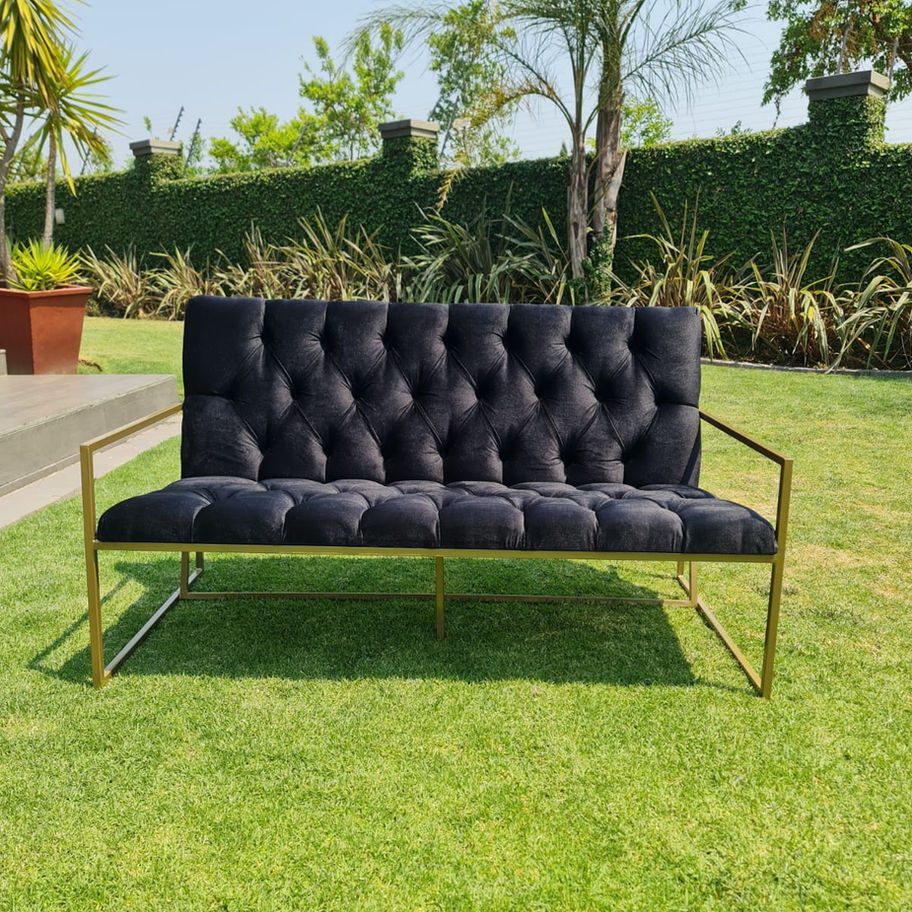 Black button couch in grass with gold frame, Nomalanga Events Creations.