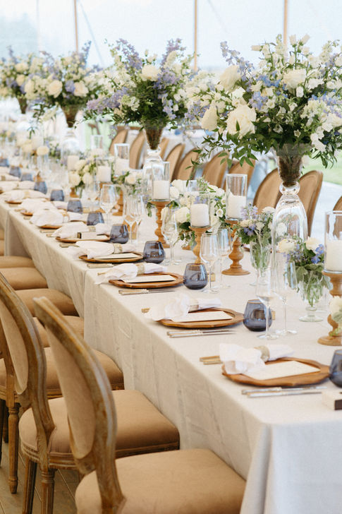 Long table with blue and white flowers and blue glasses 