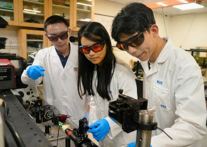 Assistant Professor Mao Xianwen (left) and team members align the optical system to study catalytic reactions at the nanoscale. Credit: College of Design and Engineering, NUS