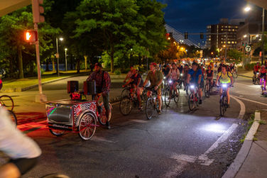 Participants on bicycles in a fun group ride with music and dance breaks during parades and events.