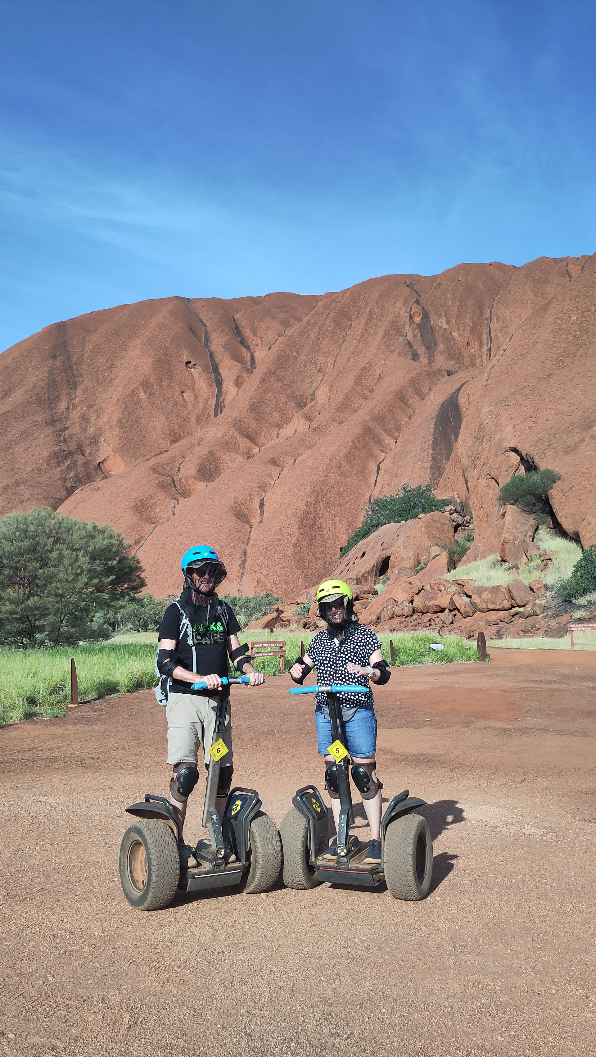 zwei Personen auf Segways vor Uluru