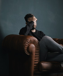 Sad man on couch with head in hands, symbolizing depression.
