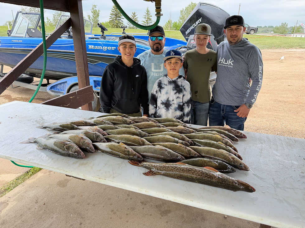Five men and boys pose by a blue Ranger boat with a table of many fresh fish outdoors, smiling after a fishing haul.