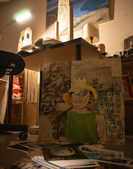 Warm lighting in a dark room that looks like a study focused on a map collage installed near the leg of a desk on the floor