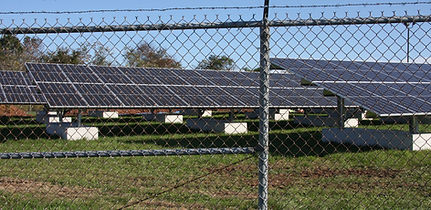 A solar project sitting behind a chain-link fence.