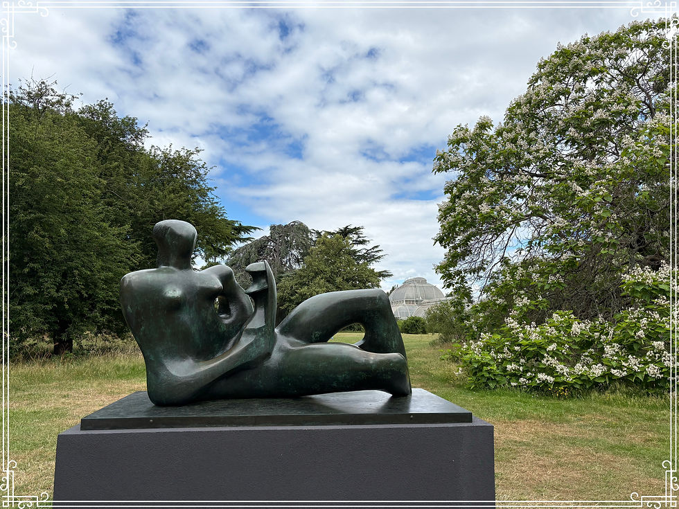 Henry Moore Bronze reclining sculpture in a green garden, with flowering trees, a glass dome greenhouse, and a cloudy blue sky.