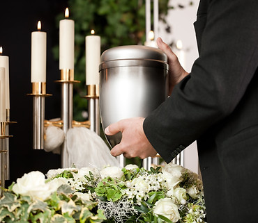 man-taking-funeral-urn-with-candles-flowers-min.jpg
