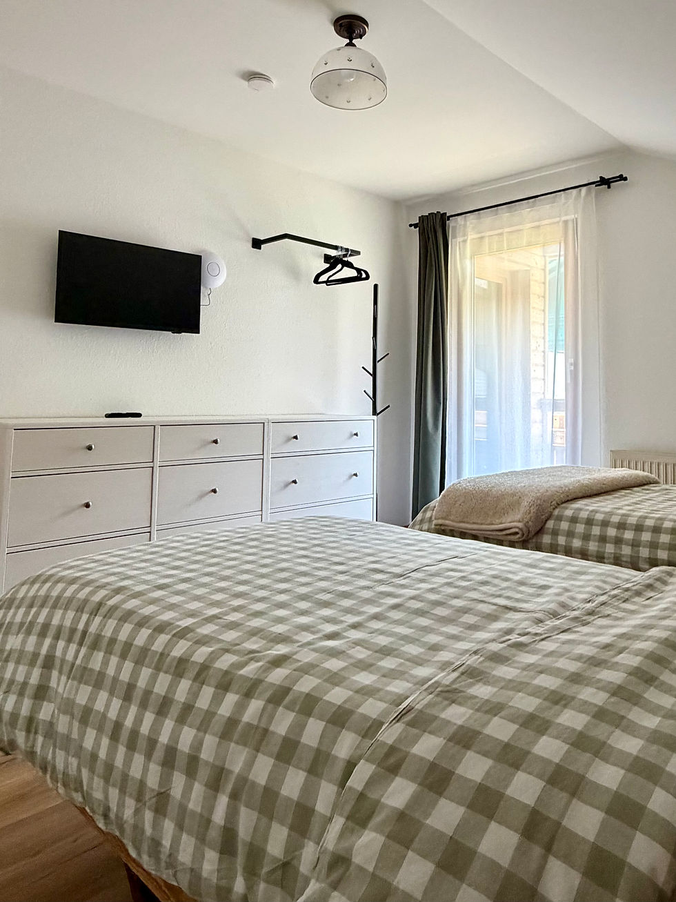 Schlafzimmer 2 mit zwei Einzelbetten oder einem Doppelbett, TV und Kommode.
