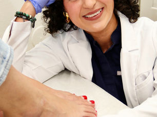 Dr Cynthia and patient sitting at foot level in a calm exam room, talking together about foot pain and treatment options.
