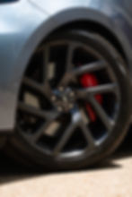 Close-up of Land Rover black alloy wheel with red performance brake caliper – mobile Land Rover brake repair service in Altam