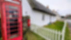 A thatched cottage, Victoria post box and classic red phone box at Kirk Yetholm