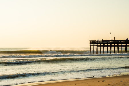 a landscape of waves and a fishing pier.