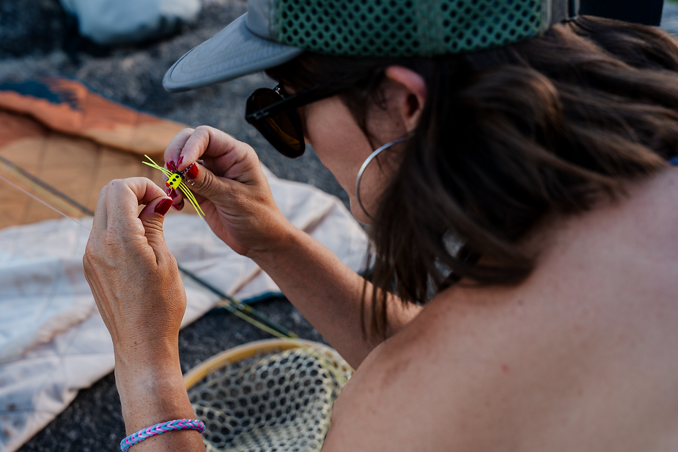 a lady fly angler looking at a popper fly.