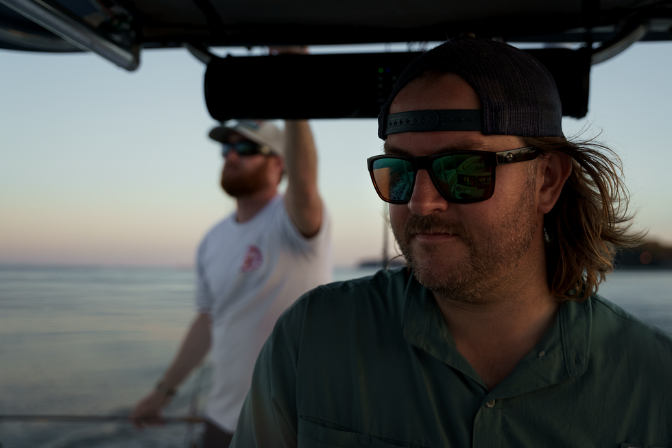 two fisherman on a boat looking for fish.