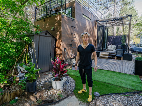 Tiny home in the mountains with a bifold glass door open onto a wooden deck