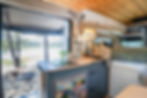 van life kitchen with induction stovetop and custom blue cabinets