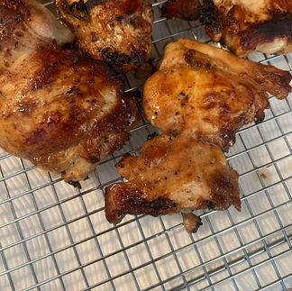 Charred chicken pieces resting on a cooling rack after searing for Senegalese yassa