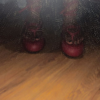 BespokeCurry wearing the red Kkerelè Nigerian leather sandals in a mirror during the August 2024 first fitting, the bright platforms visible beneath dark clothing through the textured mirror surface.