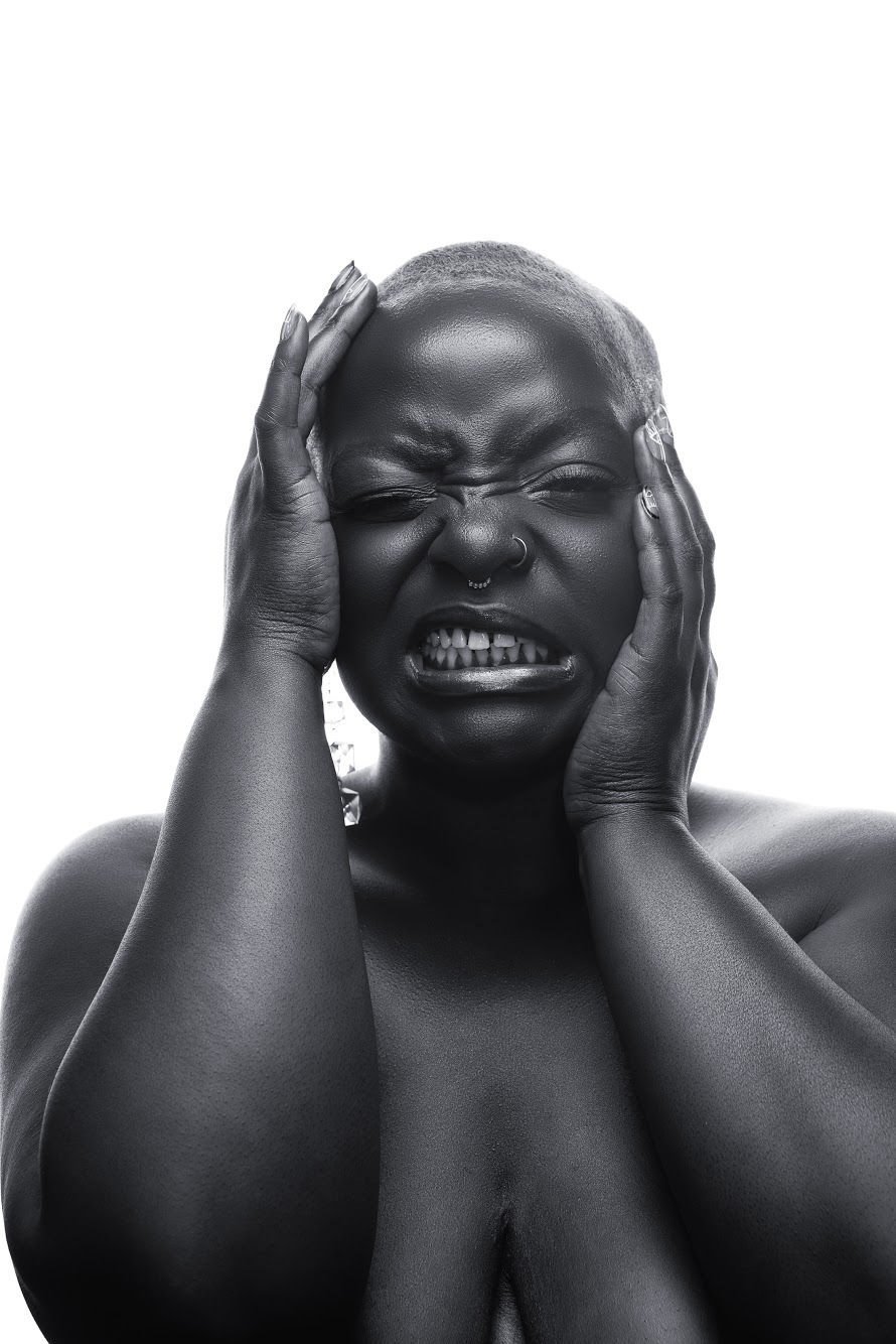 Black and white portrait of a dark-skinned person holding their face in a dysregulated expression, illustrating OCD loops and nervous system overload.