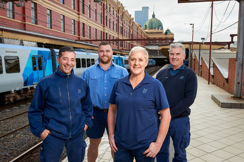 Four train drivers on Flinders Street train station platform with train in background