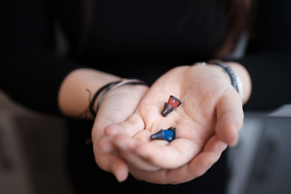Hände halten rote und blaue Hörgeräte