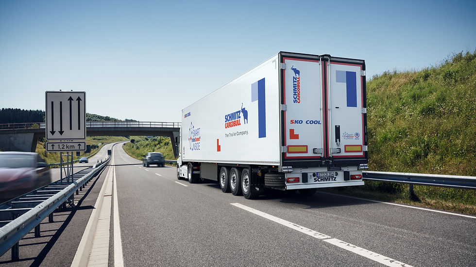 Weißer Schmitz-Cargobull-LKW auf Autobahn neben Verkehrsschild und Brücke, blauer Himmel, ländliche Straße.