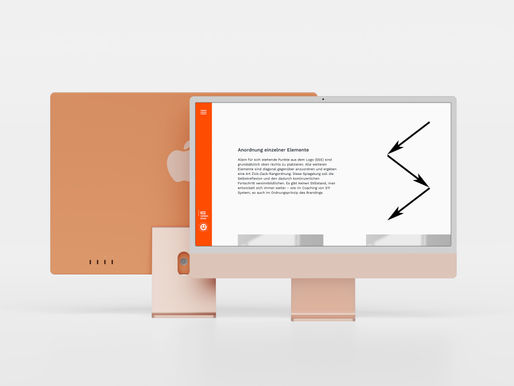 Desktop monitor displaying German design text and black arrow graphics, with an orange laptop behind it on a clean white background.