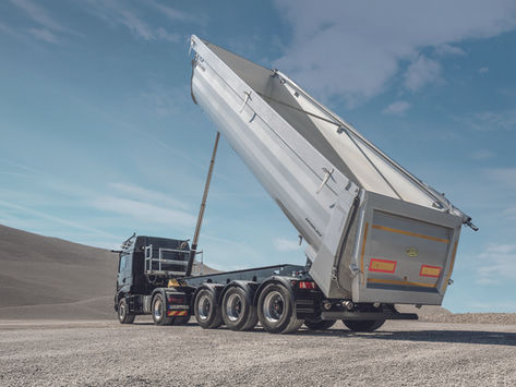 Kippauflieger-Lkw hebt die Mulde auf einem Kiesplatz vor blauem Himmel; MEILLER- und GRANDLOAD-Logo sichtbar.