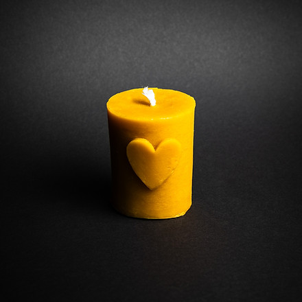 świeczka z naturalnego wosku pszczelego w formie walca z motywem serca na czarnym tle