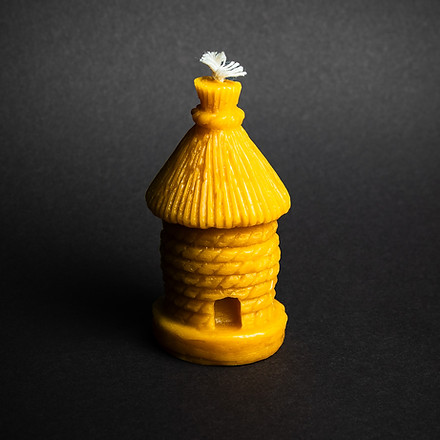 świeczka z naturalnego wosku pszczelego w kształcie ula, na czarnym tle