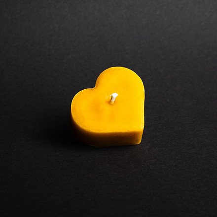 świeczka z naturalnego wosku w kształcie serca na czarnym tle