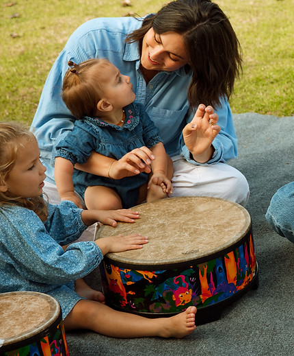 Mother and toddler sharing a joyful moment playing drum in music and movement class